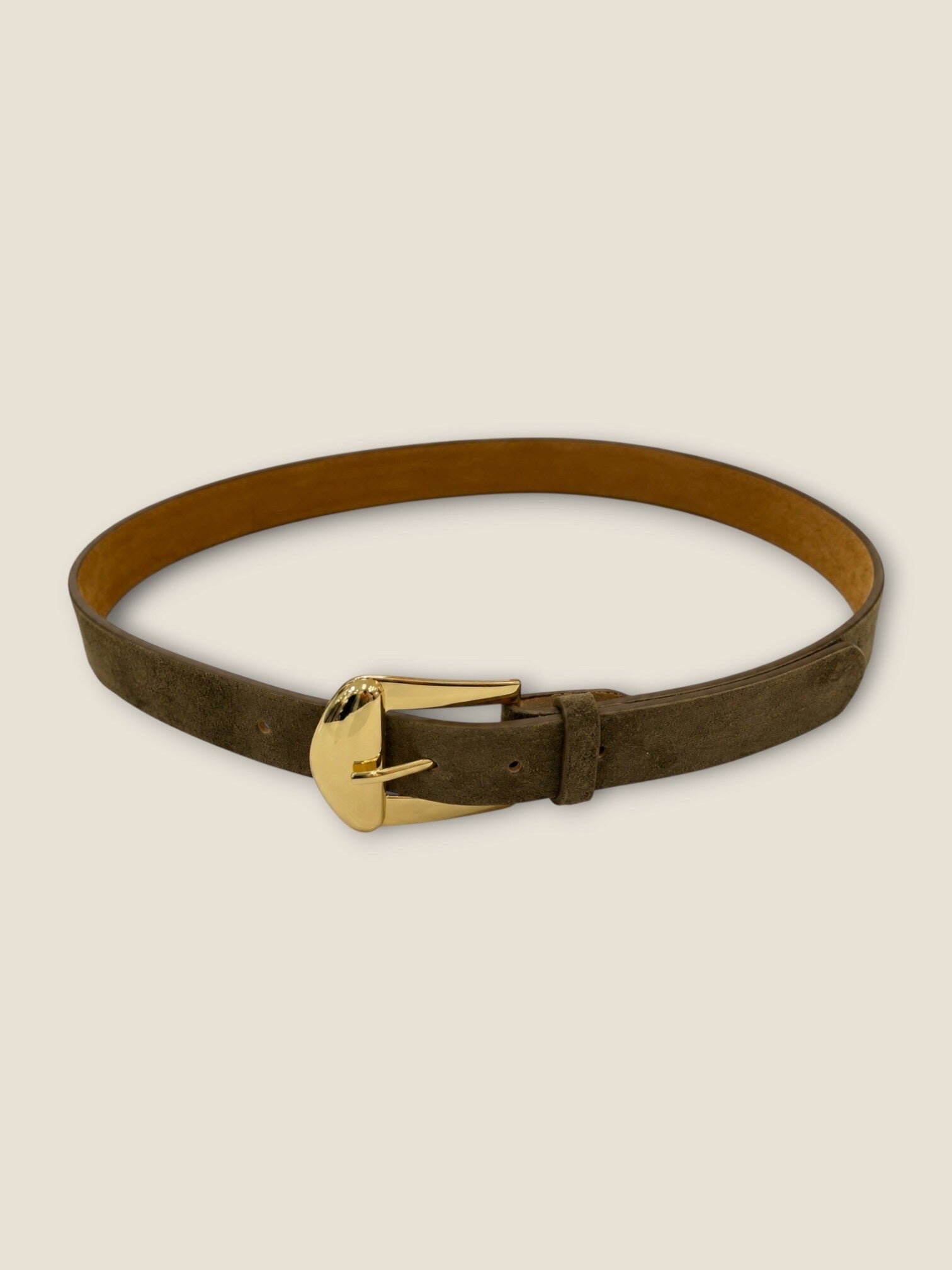 Ceinture fine en suédine kaki à boucle dorée portée sur un pantalon crème